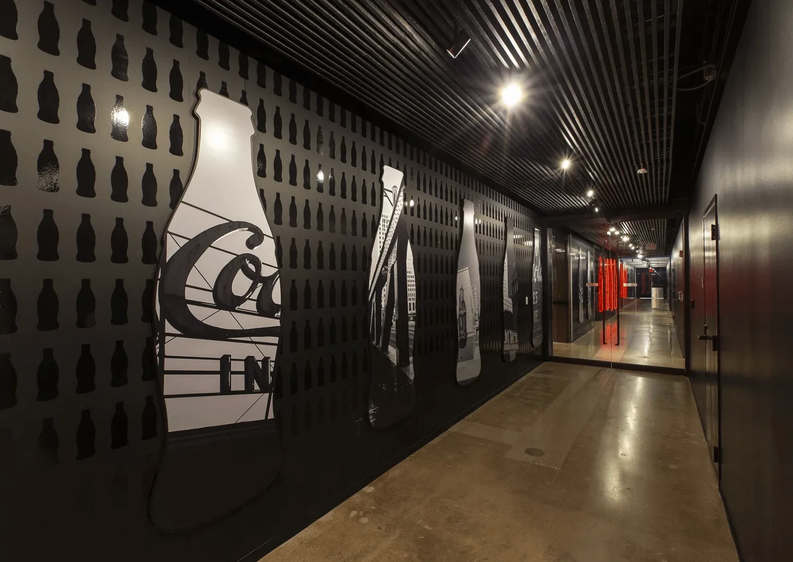 Black stylish corridor at the Niles facility, with Coca-Cola bottle-like images across the wall